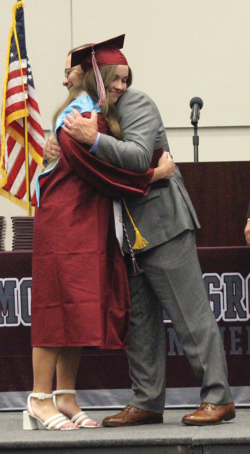 Mountain Grove Superintendent Jim Dickey hugs his daughter, Michaela Dickey, after presenting her a diploma.